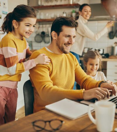 A family seated at a table, focused on a laptop, enjoying quality time and collaboration.